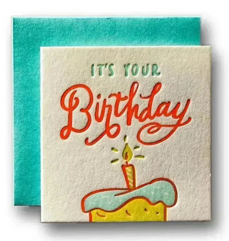 Birthday card with cake and candle illustration and 'It's Your Birthday' text on a teal envelope.
