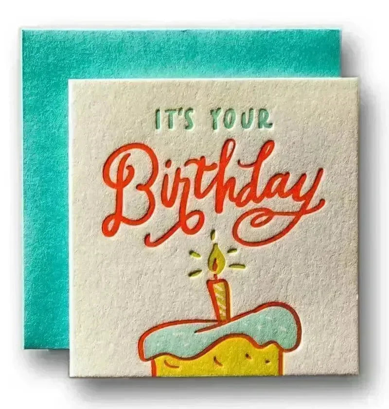 Uplifting birthday card with colorful cake, glowing candle, and cheerful text saying It's Your Birthday