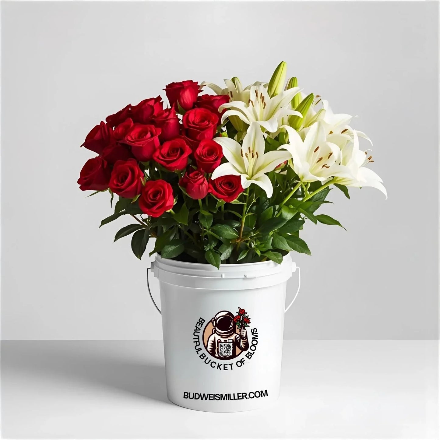 Uplifting bouquet of red roses and white lilies in a white bucket with floral branding