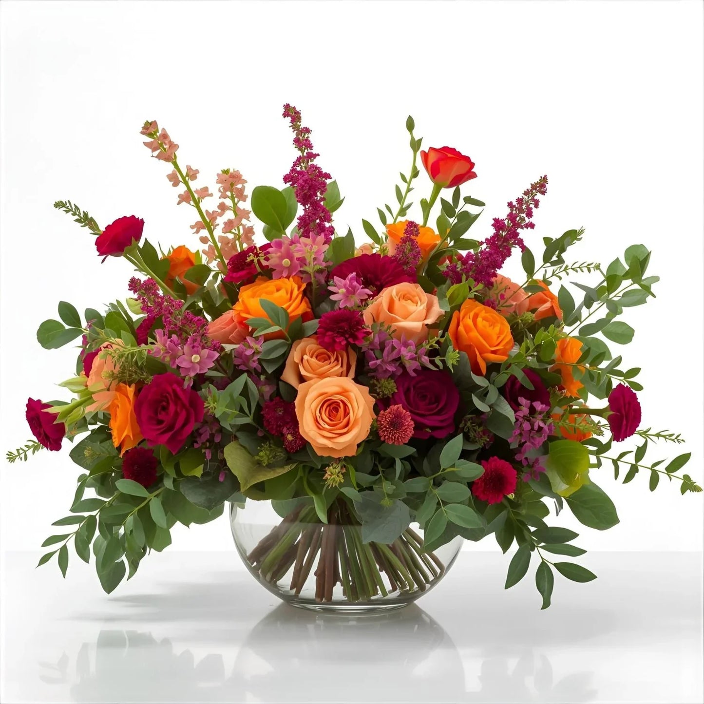 Bouquet of colorful flowers in a clear vase on a white background