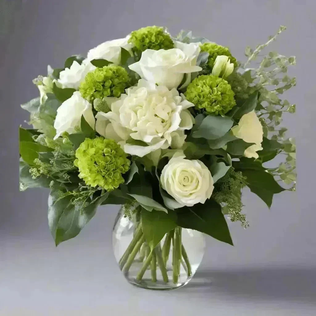 Uplifting white and green sympathy flower arrangement in clear vase with roses and hydrangeas
