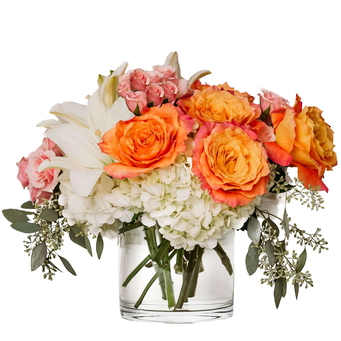 Bright bouquet of orange roses, white lilies, pink roses, and white hydrangeas in a clear glass vase