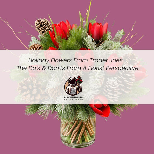 Festive holiday bouquet with bright red flowers, pine cones, and greenery in a clear vase