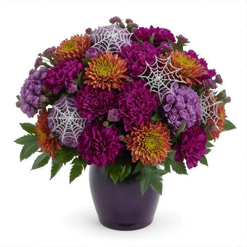Vibrant bouquet of purple, orange, and lavender flowers adorned with decorative white spiderwebs in a purple vase