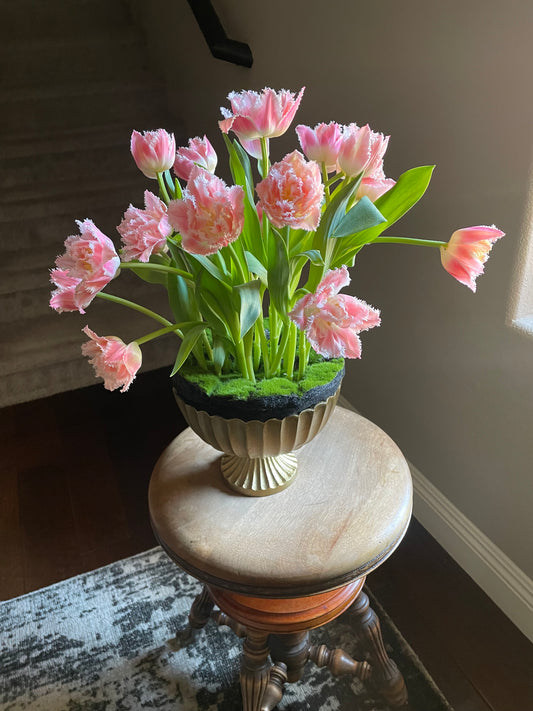 A uniquely modern arrangement of tulips in an urn appearing as if they grew up through the moss and dirt.