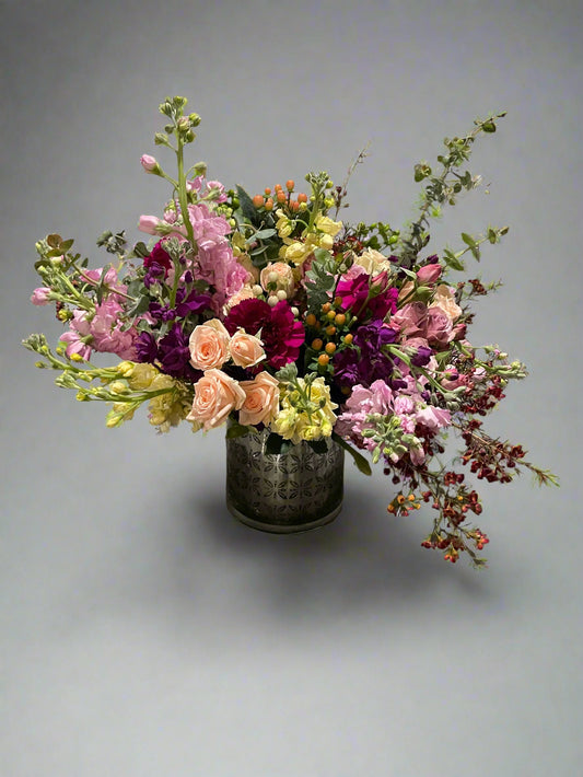 A beautiful bouquet of spray roses, stock wax flower, carnations, eucalyptus, and hypernicum berries.