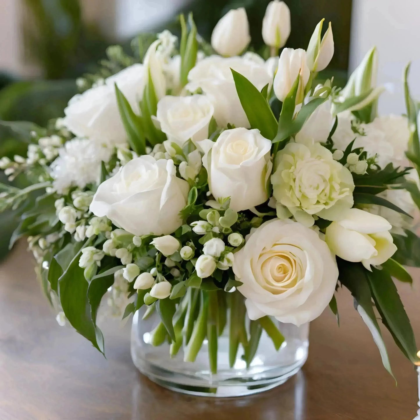 Bouquet of white flowers in a clear vase on a wooden surface