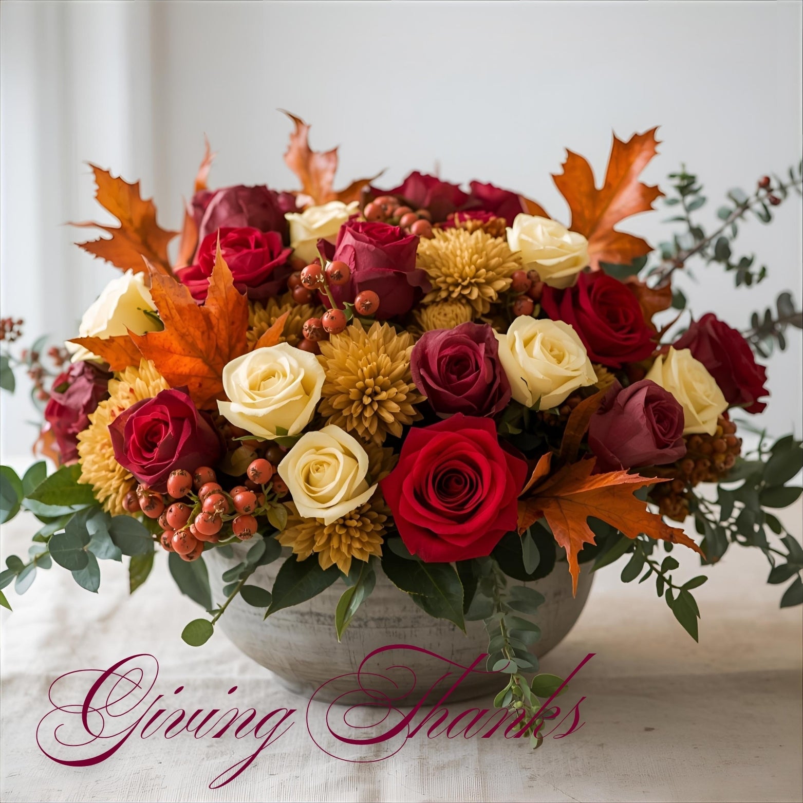 Premium Thanksgiving centerpiece with red roses, ivory roses, golden chrysanthemums, bronze mums, and hypericum berries arranged in a clear glass bowl by Bud Weismiller Flowers in Las Vegas