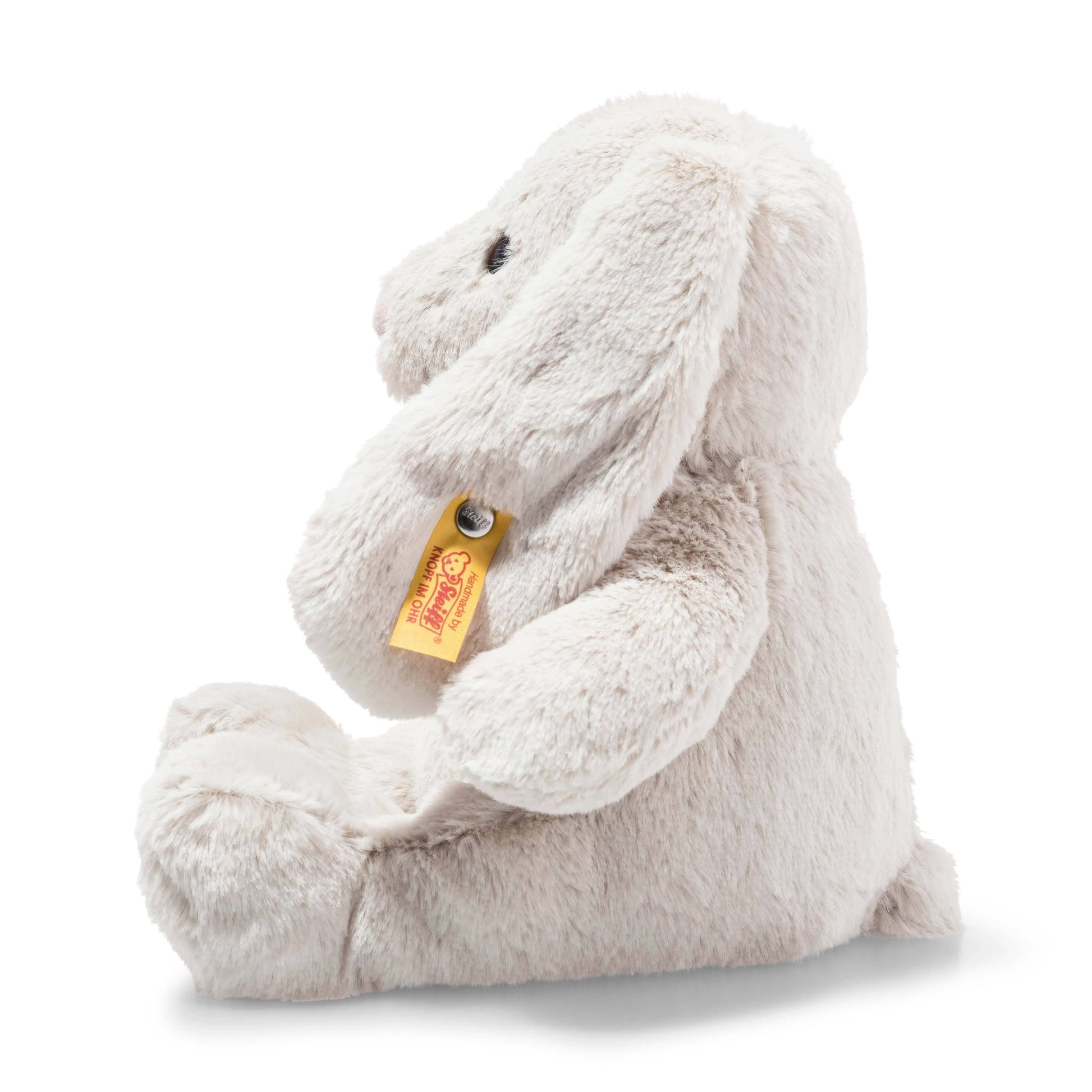 The left side profile of a cute hand-made bunny from Steiff.  The bunny has cuddly soft grey fur, floppy ears, pink nose, and button eyes.