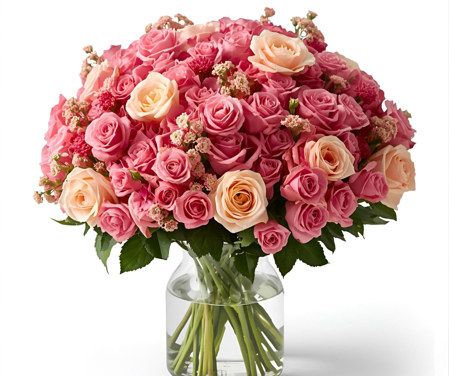 A luxury size bouquet of pink and peach spray roses in a clear vase on a white background.
