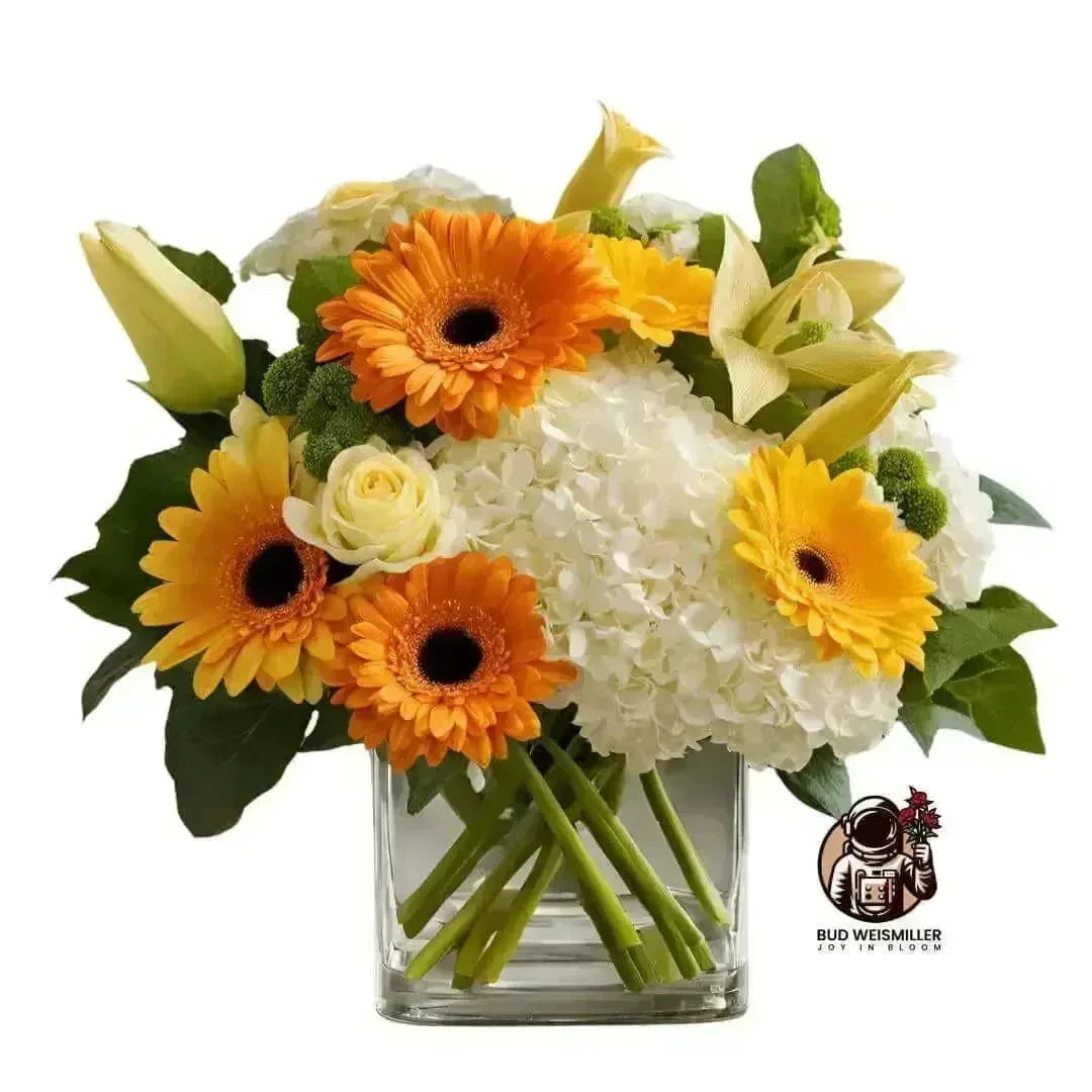 Bright bouquet of orange gerbera daisies, white hydrangeas, and yellow lilies in a clear vase