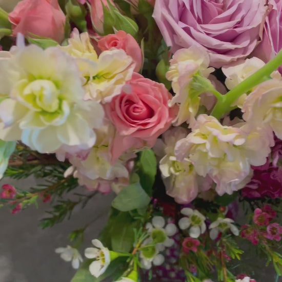 A beautiful bouquet featuring pink roses, snapdragons, stock flowers, and wax flowers in a unique upcycled vase, perfect for any occasion.